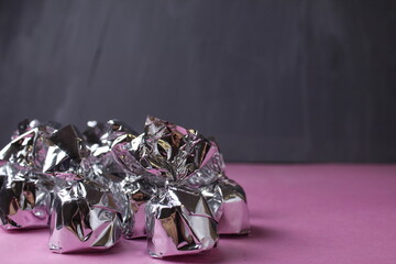 Silver-wrapped candies on a pink gray background with space for text. Handmade Candy Concept Background For Pastry Shop