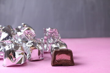 Silver-wrapped candies. Cut candy piece with pink filling praline taste raspberry strawberry
