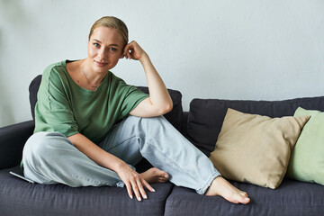 Obraz premium A cheerful young woman with a graceful pose enjoys a moment of tranquility on her sofa.