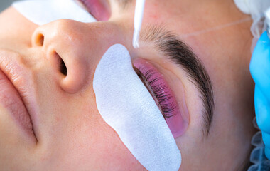 Woman during procedure of eyelashes lamination in beauty salon