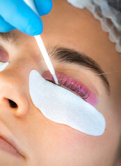 Woman during procedure of eyelashes lamination in beauty salon