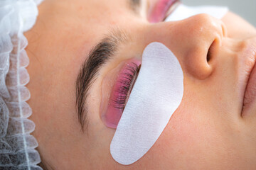 Woman during procedure of eyelashes lamination in beauty salon