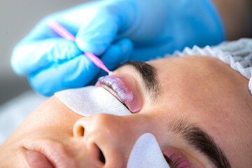 Woman during procedure of eyelashes lamination in beauty salon