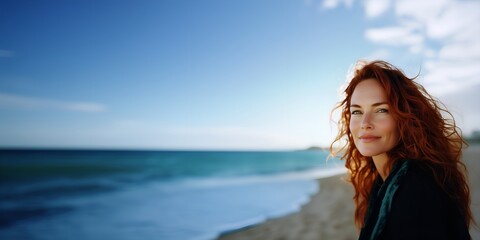 Obraz premium Red-haired woman smiling softly on a sunny beach day with space for hero text