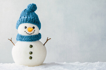 cute snowman in blue hat and gloves over white winter background with copy space