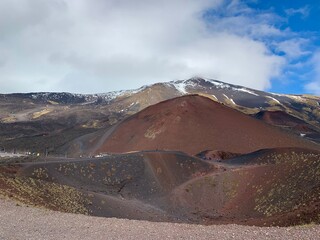 Rugged volcanic landscape of Mount Etna in Sicily, Italy. Striking reddish-brown and dark black...