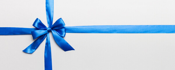 Top view of blue ribbon rolled and blue bow isolated on colored background. Flat lay with copy space