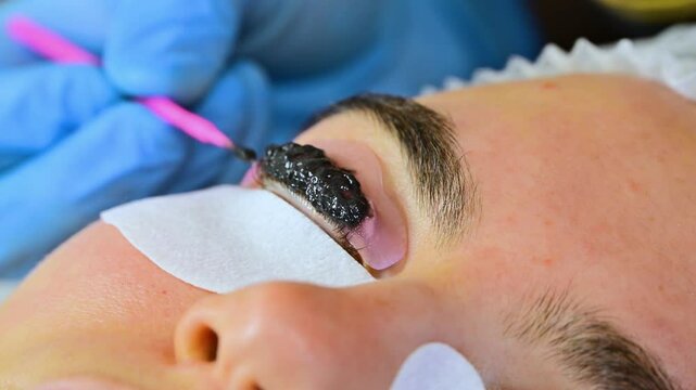 Woman during procedure of eyelashes lamination in beauty salon