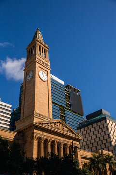 Brisbane city hall and clock tower in full sun with other city buildings behind