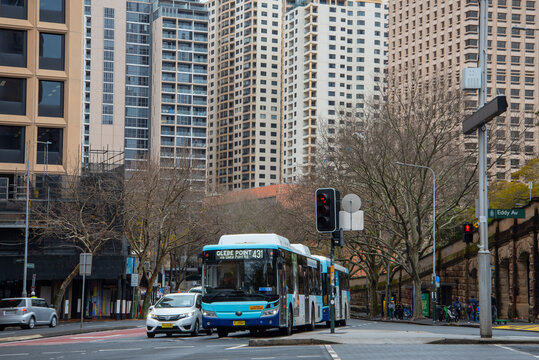 Bus at an intersection with tall buildings crowded around