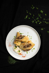 Stuffed Crepes with Mushroom Filling and Sour Cream on a White Plate.
