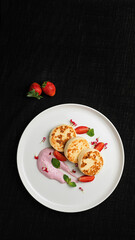 Cottage Cheese Pancakes with Berry Cream and Fresh Strawberries on a White Plate.
