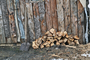wooden log house. Chopped firewood with a shovel on the threshold of the house in winter