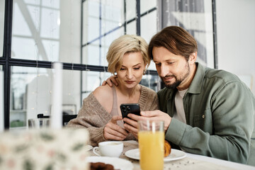 A couple sits closely at home, sharing laughter and warmth over breakfast and a smartphone.