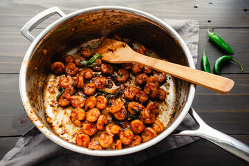 Saute Pan of Tom Rim (Vietnamese Caramelized Shrimp): Southeast Asian seafood with thick sauce, green onions, chili peppers, and a bamboo spatula