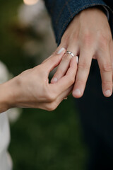A woman is carefully placing a beautiful wedding ring onto the finger of a man, symbolizing their love and commitment to each other