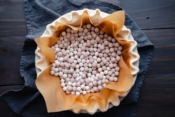 Preparing to Blind Bake a Fluted Pie Crust: Pie crust lined with parchment paper and filled with ceramic pie weights for blind baking