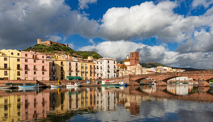Obraz premium View of the picturesque town of Bosa with its colorful houses reflected in the Temo River at golden hour. Sardinia, Italy.