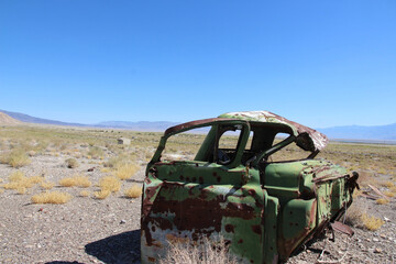 Rusty Abandoned Car in Desert Landscape Under Bright Blue Sky