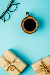 Vertical Fat lay composition with gift boxes, coffee cup, and eyeglasses on a blue background. Fathers Day concept.