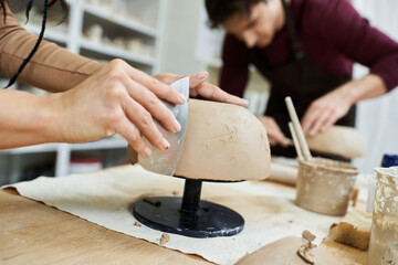 A couple meticulously shapes clay while enjoying their creative time together.