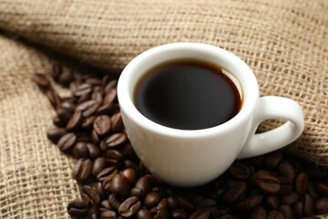 Cup of coffee and coffee beans on burlap background