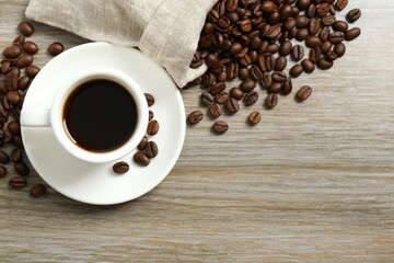 Cup of coffee and coffee beans on wooden background