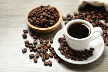 Cup of coffee and coffee beans on wooden background