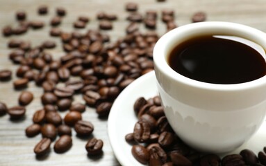 Cup of coffee and coffee beans on wooden background