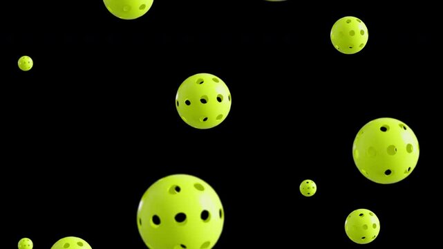 Loopable footage of falling pickle balls. Slow-motion. Black background. 4K HD