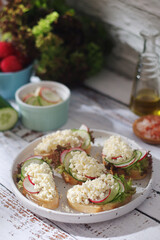 A plate with sandwiches with cottage cheese, radish and cucumber in rustic style