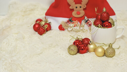 Assorted red and gold glittered Christmas baubles and a reindeer ornament on lace invoking a festive holiday mood