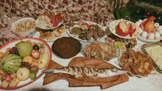 A table filled with various fruits, grilled fish, pansit, biko and other authentic local Filipino dish and desserts for a traditional New Year's Eve feast or Media Noche in the Philippines