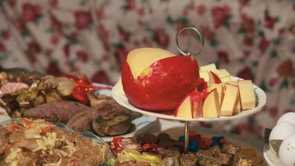 A red queso de bola or cheese ball sliced on a platter that's a staple in Filipino Noche buena and...