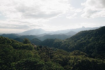 Scenic view of lush green mountains under a cloudy sky.