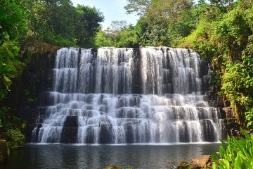 Fototapeta premium Cascading tropical waterfall surrounded by lush greenery