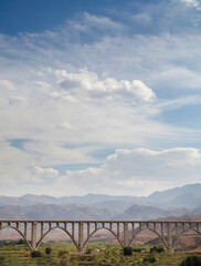 The way of the bridge over the river with meadows and mountains and cloudy sky