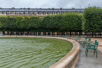 The typical green chairs of Parisian public parks remain empty on a rainy day, Palais-Royal, Paris, France