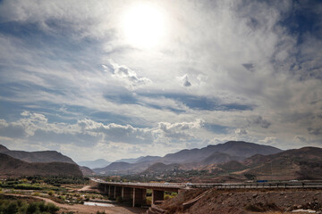 The way of the bridge over the river with meadows and mountains and cloudy sky