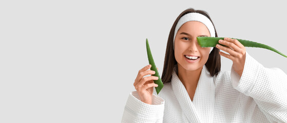 Beautiful young happy in bathrobe woman with aloe vera leaves on white background