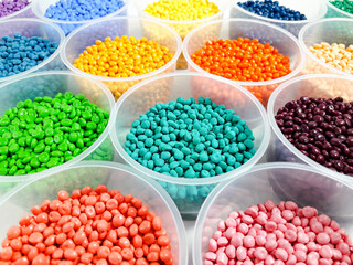 Various colored masterbatch granules in a cup on a white background.Polymer carriers of color...