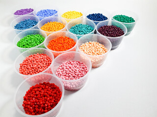 Various colored masterbatch granules in a cup on a white background.Polymer carriers of color...