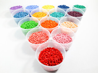 Various colored masterbatch granules in a cup on a white background.Polymer carriers of color pigments in the plastics industry