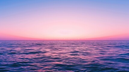 Fototapeta premium Picturesque sunset over calm ocean with pink and purple horizon in clear blue sky.