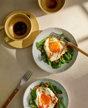 Breakfast fried eggs with greens and hot sauce. 