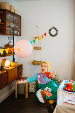 Child Joyfully Reaching For Balloon During Colorful Birthday Party.