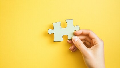 Person holding a puzzle piece representing problem-solving and strategy with a solid yellow background symbolizing energy and optimism in developing a financial mindset.