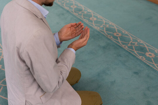 man raising hand in prayer in mosque