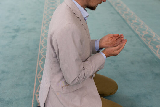 man raising hand in prayer in mosque