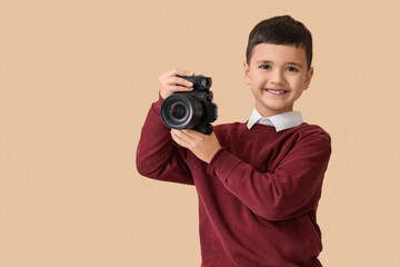 Cute little photographer with camera on beige background. Opposite Day celebration